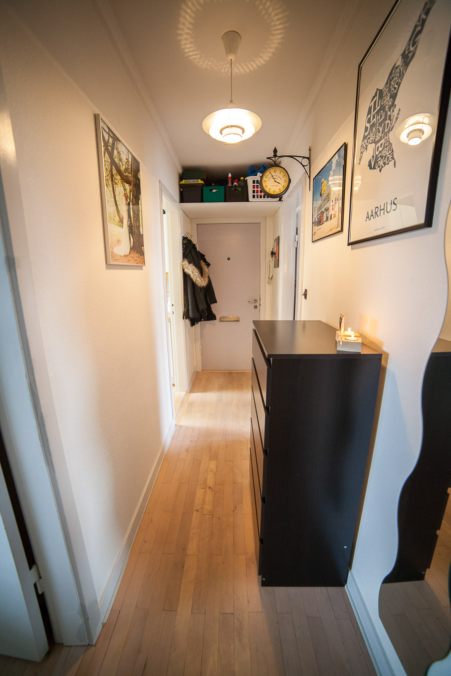 Fordelingsgangen. Døren for enden er hoveddøren, og billedet er taget henne fra badeværelset. Der er god opbevaring over døren, og derudover er der et indbygget skab i gangen.